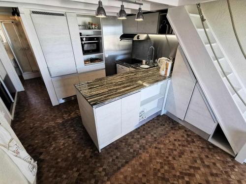 une cuisine avec des armoires blanches et un réfrigérateur en acier inoxydable dans l'établissement Résidence Les Aigues Marines - Appartement T3 mezzanine à Port Leucate - Réf: 1AM_125 MAE-1254, à Port-Leucate