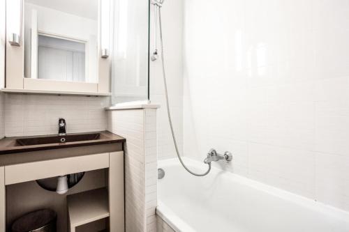 une salle de bain blanche avec un lavabo et une baignoire dans l'établissement Résidence Les Parcs de Grimaud - maeva Home - Appartement 2 Pièces 5 Personnes - Confort MAE-0293, à Grimaud