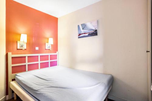 Ce petit lit se trouve dans une chambre aux murs orange et blancs. dans l'établissement Résidence Les Parcs de Grimaud - maeva Home - Appartement 2 Pièces 5 Personnes - Confort MAE-0293, à Grimaud