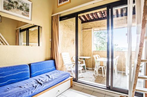Cette chambre dispose d'un canapé et d'un balcon avec une table. dans l'établissement Résidence Les Parcs de Grimaud - maeva Home - Studio 5 Personnes - Confort MAE-0295, à Grimaud