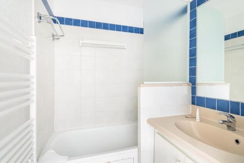 une salle de bain blanche avec une baignoire et un lavabo dans l'établissement Résidence Bleu Marine - maeva Home - Appartement 2 Pièces 4 Personnes - Confort MAE-0547, à Lacanau