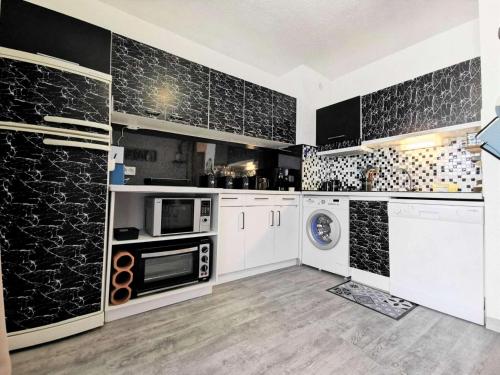 - une cuisine avec des placards blancs et des murs noirs dans l'établissement Résidence Madinina - STUDIO 4 PERSONNES 4 couchages PORT LEUCATE MAE-7744, à Leucate