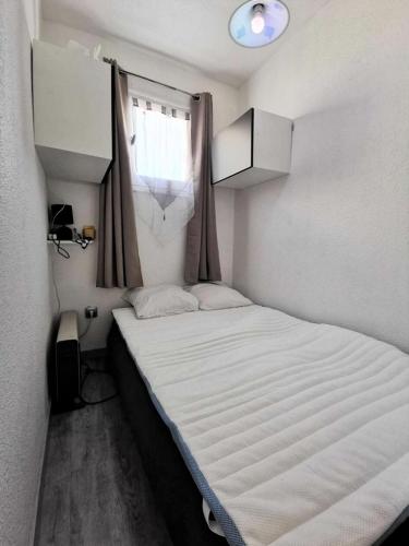 - un petit lit dans une petite chambre avec fenêtre dans l'établissement Résidence Madinina - STUDIO 4 PERSONNES 4 couchages PORT LEUCATE MAE-7744, à Leucate