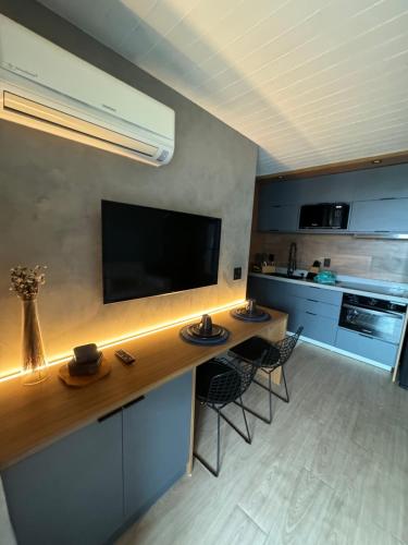 a kitchen with a large wooden counter with two chairs at Luxuoso Studio particular reformado no Grand Mercure in Brasília