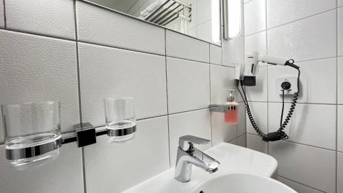 Baño blanco con lavabo y espejo en Landhotel Weisses Ross garni, en Bad Brückenau