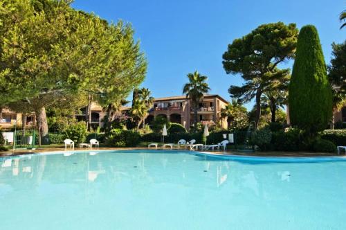 une grande piscine avec des chaises et un bâtiment dans l'établissement Résidence La Pinède - maeva Home - Appartement 3 Pièces 6 Personnes - Sélection MAE-4231, à Hyères