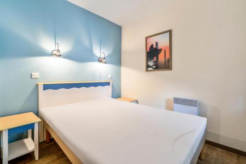 - une chambre avec un lit blanc et un mur bleu dans l'établissement Résidence Cap Azur - maeva Home - Appartement 3 Pièces 7 Personnes - Confort MAE-4376, à Fouesnant