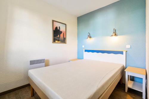 ein Schlafzimmer mit einem weißen Bett und einer blauen Wand in der Unterkunft Résidence Cap Azur - maeva Home - Appartement 3 Pièces 7 Personnes - Confor 80 in Fouesnant