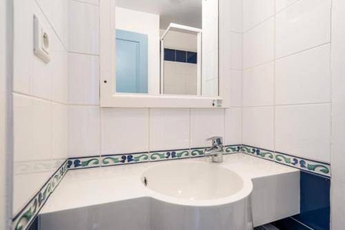 ein weißes Badezimmer mit einem Waschbecken und einem Spiegel in der Unterkunft Résidence Cap Azur - maeva Home - Appartement 3 Pièces 7 Personnes - Confor 80 in Fouesnant