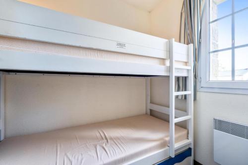 Ce lit superposé se trouve dans une chambre située à côté d'une fenêtre. dans l'établissement Résidence Cap Azur - maeva Home - Appartement 3 Pièces 7 Personnes - Sélection MAE-4382, à Fouesnant