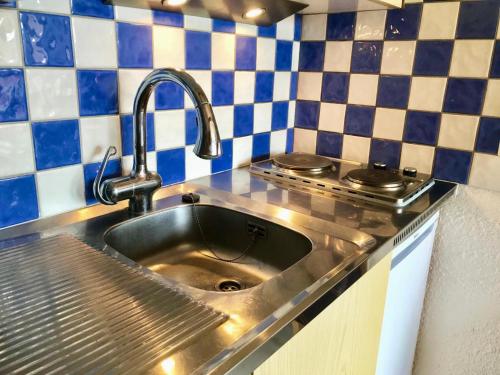 a stainless steel sink in a kitchen with blue and white tiles at Résidence Les Glovettes - Studio pour 4 Personnes 134 in Villard-de-Lans
