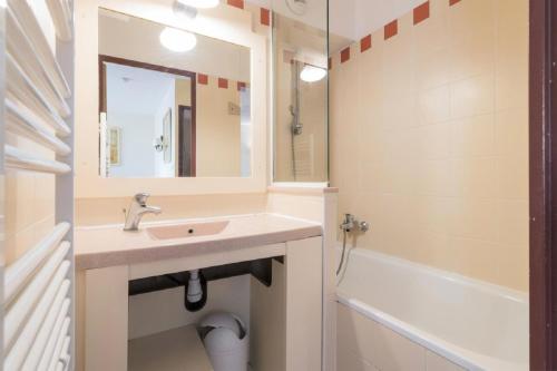 a bathroom with a sink and a mirror and a tub at Résidence Les Rivages de Rochelongue - maeva Home - Appartement 3 pièces 6 11 in Cap d'Agde