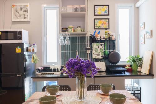 a kitchen with a table with a vase of purple flowers at t-t-haus in Bangkok