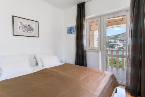 - une chambre avec un lit et une grande fenêtre dans l'établissement Vila Curic, à Dubrovnik