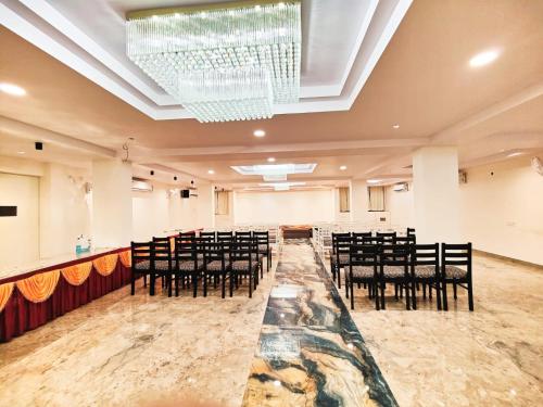 un salón de banquetes con sillas negras y una lámpara de araña en Hotel Mahamaya, en Satna