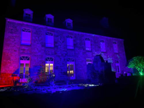 un edificio iluminado en púrpura y rosa por la noche en Route du Mont-Saint-Michel, en Mortain