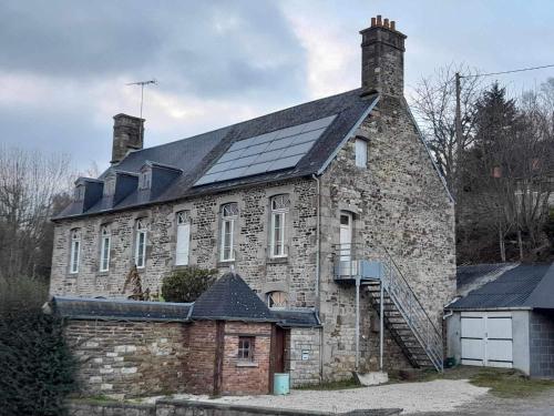 una antigua casa de piedra con paneles solares en el techo en Route du Mont-Saint-Michel, en Mortain