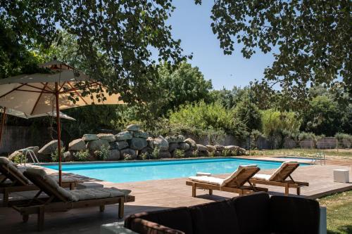 uma piscina com espreguiçadeiras e um guarda-sol em Quinta do Louredo - Évora em Évora