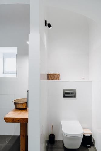 a white bathroom with a toilet and a wooden table at Quinta do Louredo - Évora in Évora