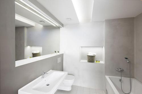 a white bathroom with a sink and a toilet at Hotel 100 in Pardubice