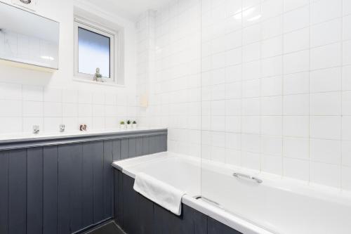 a white bathroom with a tub and a window at The Canonbury Villa in London