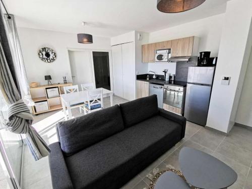 un salon avec un canapé noir et une cuisine dans l'établissement Résidence Les Voiles Blanches - 2 Pièces 4 couchages PORT LEUCATE MAE-5854, à Leucate