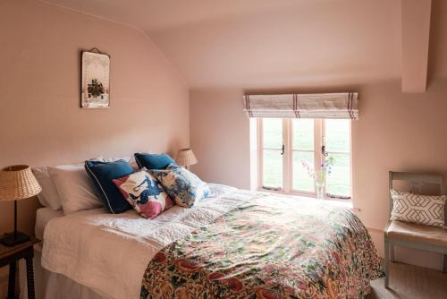 ein Schlafzimmer mit einem Bett mit Kissen und einem Fenster in der Unterkunft Meadow Cottage in Wimborne Minster
