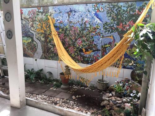 a hammock in front of a wall with a mural at Casa Charmosa Verde-Azul in Paracuru