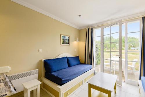 un salon avec un canapé bleu et une fenêtre dans l'établissement Les Maisons de Port Bourgenay - maeva Home - Maison 2 Pièces 5 Personnes - Sélection MAE-5565, à Talmont-Saint-Hilaire
