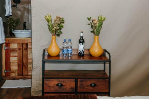 un tavolo con due vasi arancioni e bottiglie sopra di Down-to-Earth Luxury Tented Accommodation a George