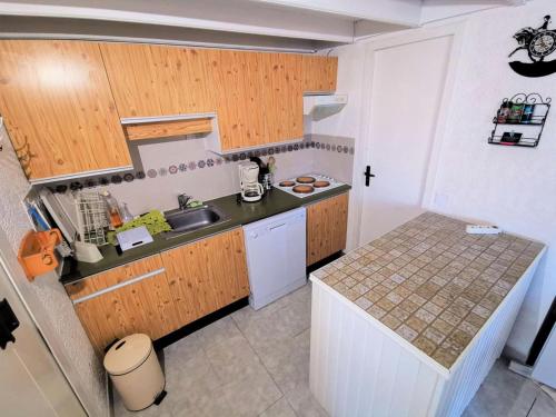Elle comprend une petite cuisine avec des placards en bois et un évier. dans l'établissement Résidence Maisons Des Sables 1 - Appartement deux pièces mezzanine - 4 personnes - PORT LEUCATE MAE-5564, à Leucate