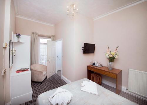 um quarto com uma cama e uma secretária com uma televisão em Monaco Hotel em Weston-super-Mare
