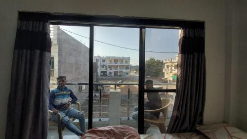 Un uomo seduto su una sedia davanti a una finestra di UNiTY MADHAV HOMESTAY a Kevadia