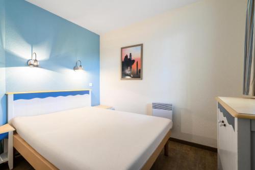 un lit dans une chambre avec un mur bleu dans l'établissement Résidence Cap Azur - maeva Home - Appartement 2 Pièces 5 Personnes - Sélection MAE-6707, à Fouesnant