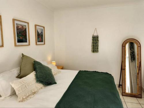 a white bed with a green blanket and a mirror at The Grace in Pretoria