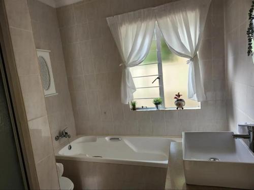 a white bath tub in a bathroom with a window at The Grace in Pretoria