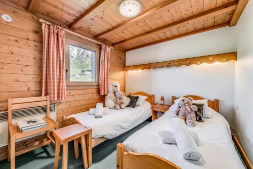 two beds in a room with wooden walls at Chalet L'armoise - Chalets pour 14 Personnes 954 in Tignes