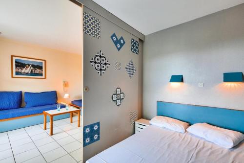 une chambre avec un lit et un canapé bleu dans l'établissement Résidence le Hameau de Cap Esterel - maeva Home - Appartement 2 Pièces 5 Personnes - Confort MAE-6795, à Saint-Raphaël
