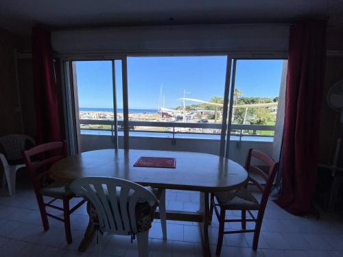 une table et des chaises dans une pièce avec une fenêtre dans l'établissement Résidence Port Helena Coudouliere - Appartement front de mer MAE-7644, à Six-Fours-les-Plages