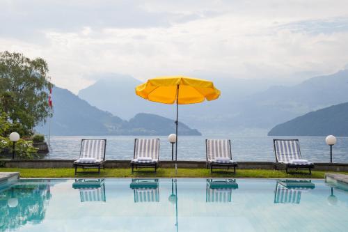 a pool with umbrellas on top of it at Romantik Hotel Beau Rivage Weggis - Beau Rivage Collection in Weggis