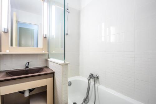 une salle de bain avec un lavabo, une baignoire et un miroir dans l'établissement Résidence Les Parcs de Grimaud - maeva Home - Studio 4 Personnes - Sélection MAE-7504, à Grimaud