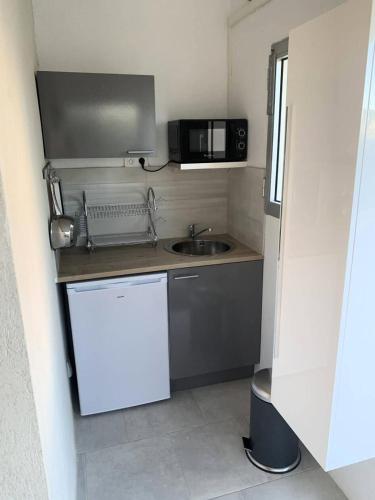 une petite cuisine avec un évier et un micro-ondes dans l'établissement Résidence Mistral - Joli studio à Six Fours Les Plages 100m de la plage - Accès direct MAE-8844, à Six-Fours-les-Plages