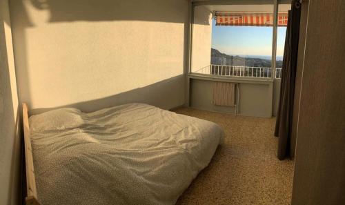 un lit dans une chambre avec une grande fenêtre dans l'établissement Résidence Rouviere - Grand appartement vue mer petit budget MAE-8124, à Marseille