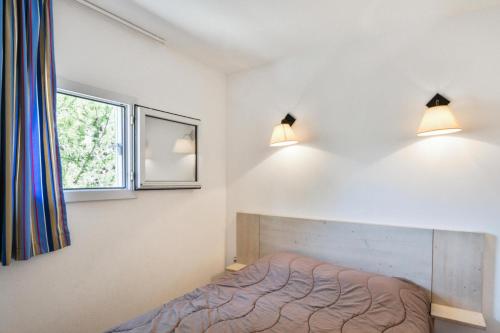 een slaapkamer met een bed en twee lampen aan de muur bij Résidence Debussy - maeva Home - Appartement 2 Pièces 4 Personnes - Budget 37 in Carnoux