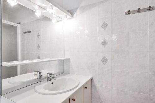 een witte badkamer met een wastafel en een spiegel bij Résidence Debussy - maeva Home - Appartement 2 Pièces 4 Personnes - Budget 37 in Carnoux