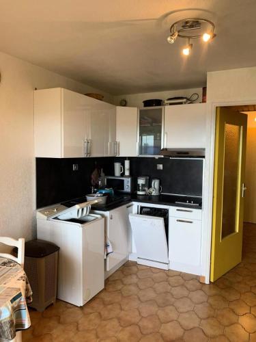 une cuisine avec des armoires blanches et des appareils noirs dans l'établissement Résidence Marines D'aryana - Appartement front de mer avec tennis et piscine MAE-9174, à Six-Fours-les-Plages