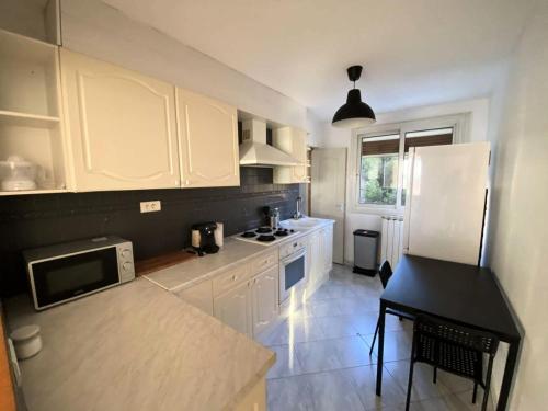 une cuisine avec des armoires blanches et un comptoir noir dans l'établissement Résidence Rouviere - Grand appartement 8 couchages vue mer budget maitrisé MAE-9674, à Marseille