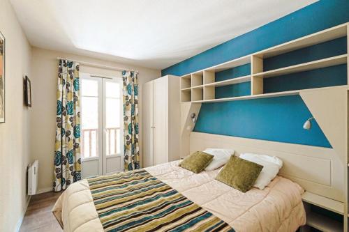 une chambre avec un lit avec un mur bleu dans l'établissement Résidence Lacanau Les Pins - maeva Home - Maison 3 pièces 6 personnes Sélection MAE-9122, à Lacanau