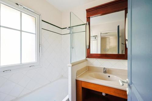 une salle de bain avec une baignoire, un lavabo et un miroir dans l'établissement Résidence Lacanau Les Pins - maeva Home - Maison 3 pièces 6 personnes Sélection MAE-9122, à Lacanau