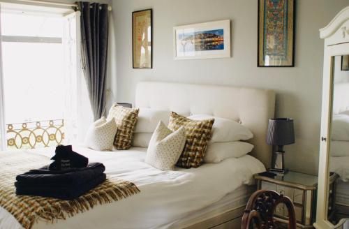 una camera da letto con un letto bianco con cuscini e una finestra di Ranscombe House a Brixham